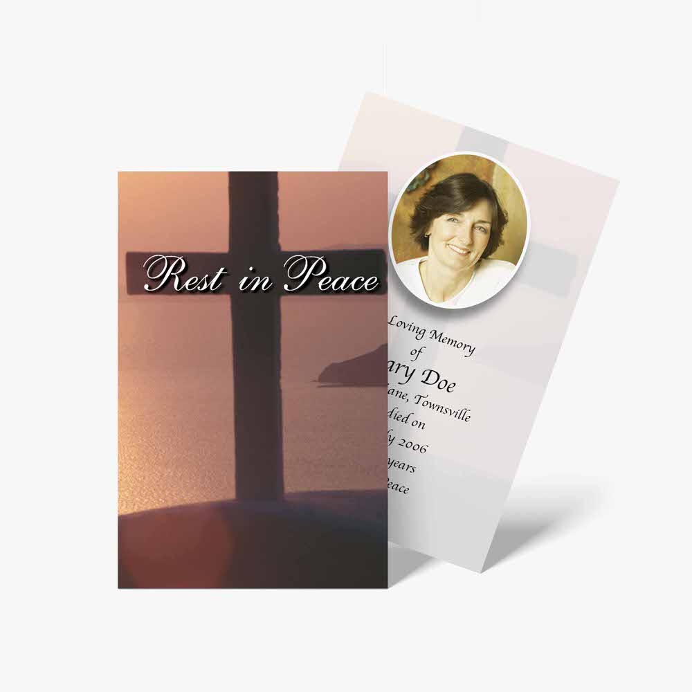 a funeral card with a photo of a cross and a sunset