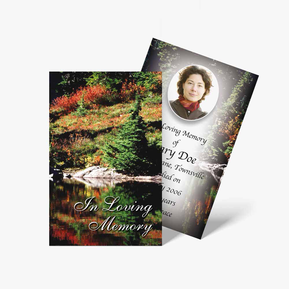 a memorial card with a photo of a lake and trees