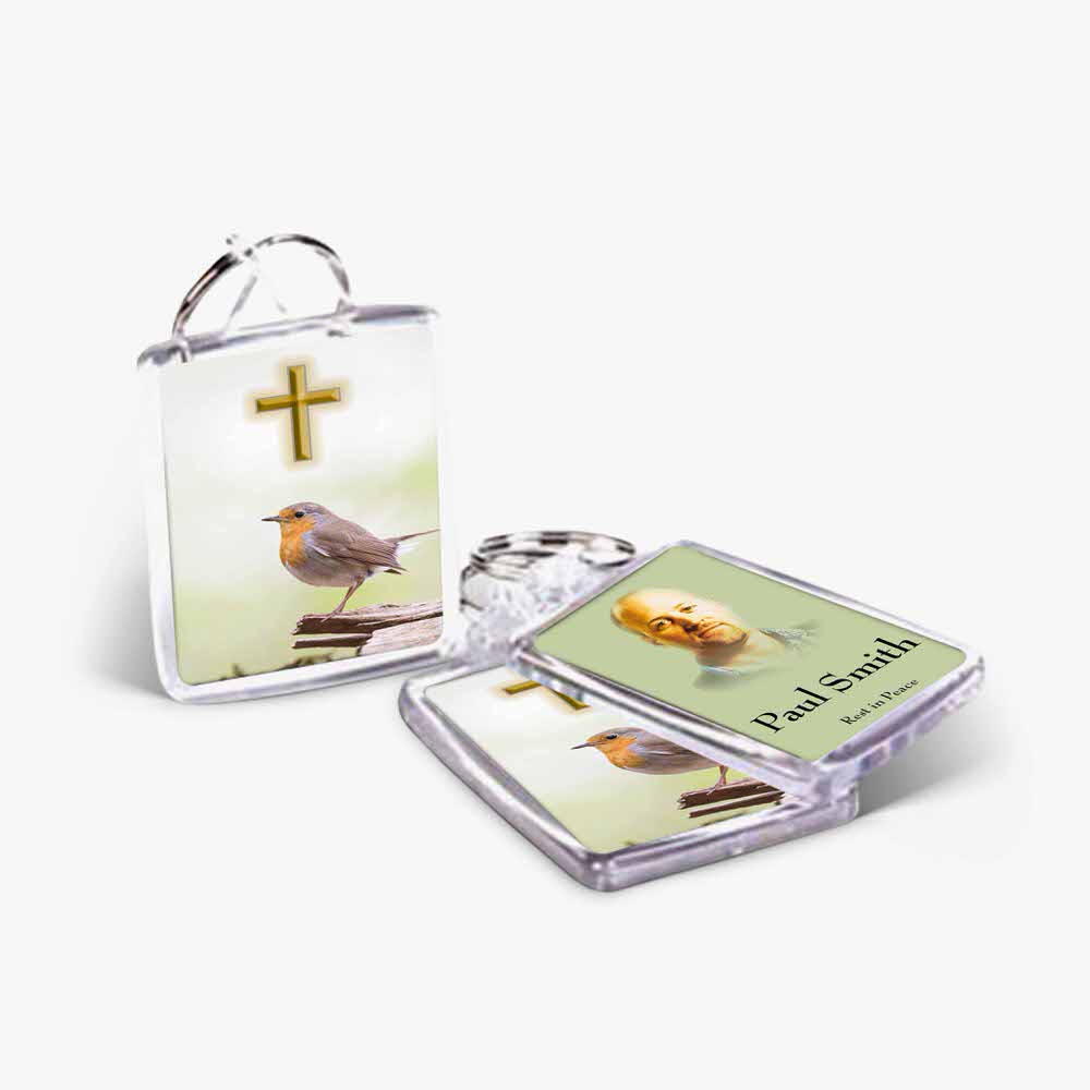 two small key chains with a bird and cross on them