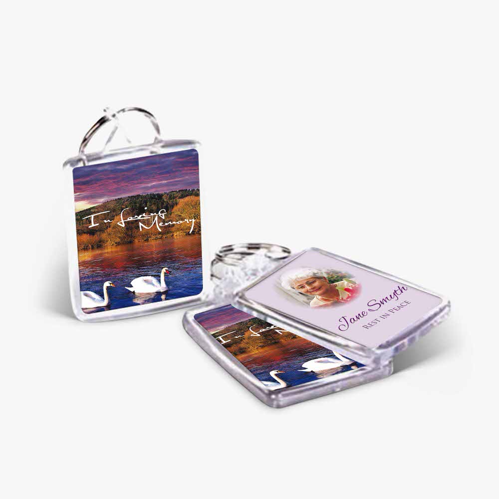 two key chains with a picture of a swan and a sunset